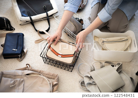 A young woman puts various women's handbags for storage in her home wardrobe. Accessories and bags. A young woman puts various women's handbags for storage in her home wardrobe. Accessories and bags. 122548431