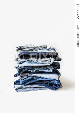Stack of various shades of blue jeans on white background Stack of various shades of blue jeans on white background 122548441