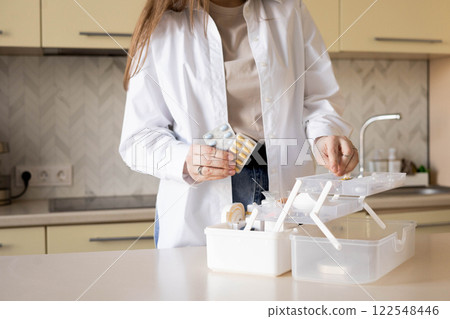 Female housewife checking medicines at domestic first aid kit neatly placing storage organization Female housewife checking medicines at domestic first aid kit neatly placing storage organization 122548446