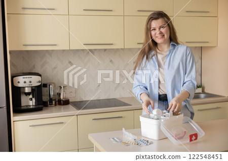 Female housewife checking medicines at domestic first aid kit neatly placing storage organization 122548451
