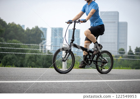 Riding a fold bike with modern city in the distrance 122549953