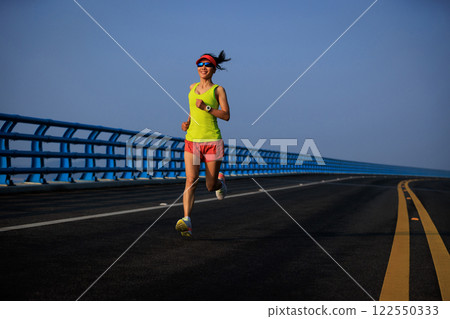 Fitness woman runner running on seaside bridge 122550333