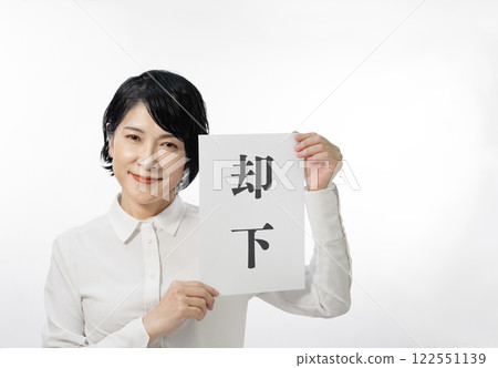 A middle-aged woman smiling and holding up a card that says "Rejected" 122551139
