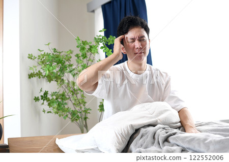 年輕的亞洲男子抱著頭躺在床上 122552006