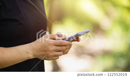Hands using mobile phone  in summer forest 122552019