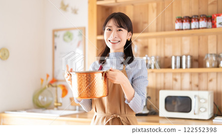 Smiling woman cooking in the kitchen (pot) 122552398