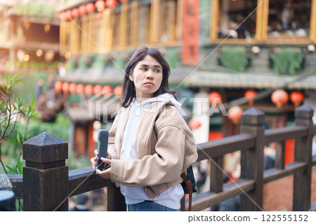 woman traveler visiting in Taiwan, female Tourist with backpack sightseeing at Jiufen Old Street village with Tea House background. Popular landmarks and attractions near Taipei City. Travel concept 122555152