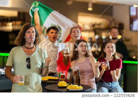 Group of friends cheer together for their favorite Mexican team in beer bar Group of friends cheer together for their favorite Mexican team in beer bar 122555626