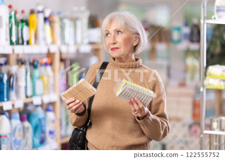 Elderly woman chooses clothespins - wooden or plastic, in hardware store Elderly woman chooses clothespins - wooden or plastic, in hardware store 122555752