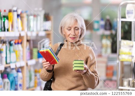 Elderly housewife chooses sponges for washing dishes and tiles in supermarket Elderly housewife chooses sponges for washing dishes and tiles in supermarket 122555769