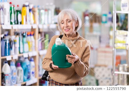 Mature positive woman consumer with household chemical products for washing indoors Mature positive woman consumer with household chemical products for washing indoors 122555790