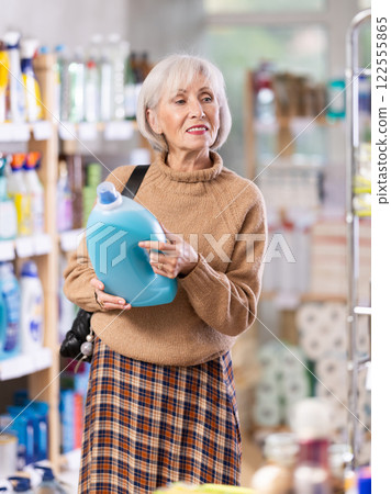 Mature positive woman consumer with household chemical products for washing indoors Mature positive woman consumer with household chemical products for washing indoors 122555865
