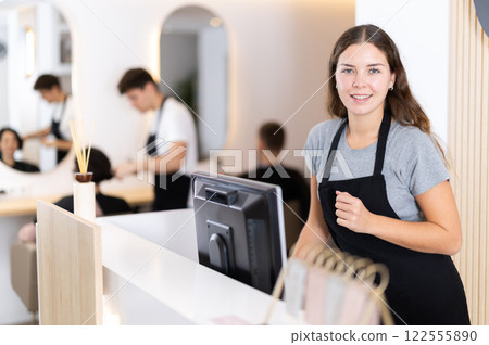 Young woman at cash register in beauty salon 122555890