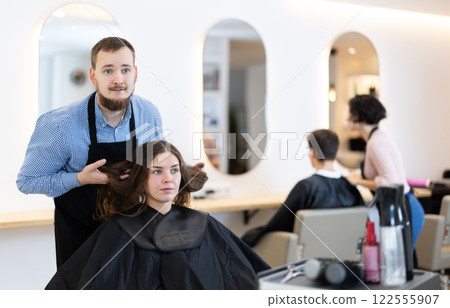 Young male hairdresser discussing haircut of female client Young male hairdresser discussing haircut of female client 122555907