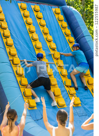 Men climbing up on slide in adventure park Men climbing up on slide in adventure park 122555987