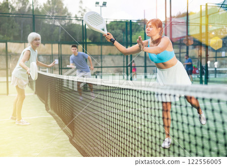 Young woman playing friendly paddleball match on outdoor court 122556005