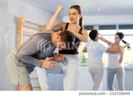 Young girl practicing self-defense techniques in pairs with middle-aged man Young girl practicing self-defense techniques in pairs with middle-aged man 122556040