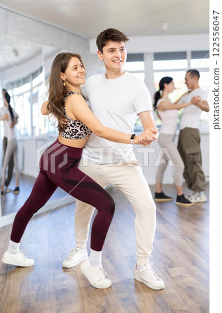 Girl paired up with young man, they train to perform slow waltz dance, rehearse performance. 122556047