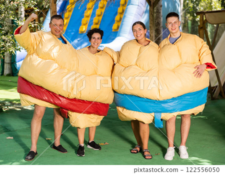 Group photo of smiling men and women wearing funny sumo suits Group photo of smiling men and women wearing funny sumo suits 122556050