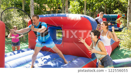 Happy man competing with friends in collect hoops on inflatable arena Happy man competing with friends in collect hoops on inflatable arena 122556055