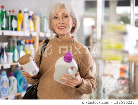 Mature positive woman consumer with household chemical products for washing indoors 122556225