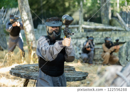 Woman targeting and shooting with paintball gun Woman targeting and shooting with paintball gun 122556288