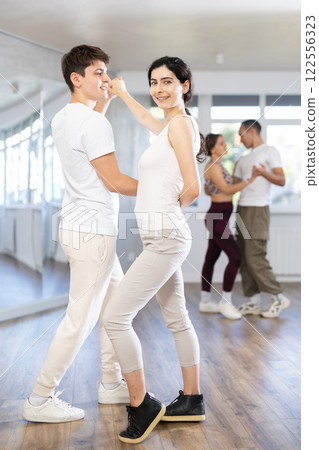 Young couple performs an expressive salsa in bright, modern dance studio during group class 122556323