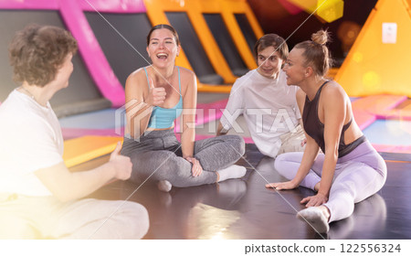 Two women and two teenager boys talking in trampoline center 122556324