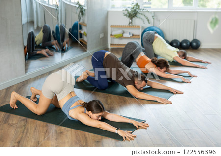 Lovers of active lifestyle on yoga mat perform doing Uttana Shishasana, puppy pose in gym 122556396