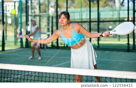 Young woman hitting ball with left-handed forehand while playing padel Young woman hitting ball with left-handed forehand while playing padel 122556415
