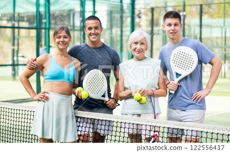 Portrait of four happy padel players on tennis court outdoor Portrait of four happy padel players on tennis court outdoor 122556437