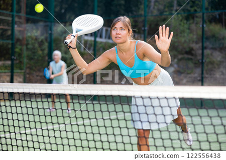 Young woman playing friendly paddleball match on outdoor court Young woman playing friendly paddleball match on outdoor court 122556438