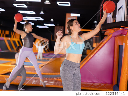 Young woman playing ball in trampoline center 122556441