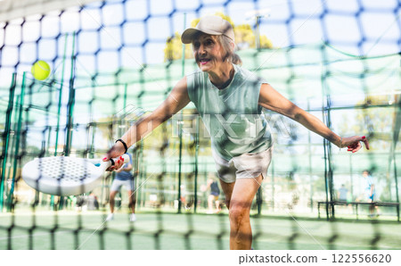 Elderly woman padel tennis player training on court 122556620