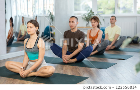 Lovers of active lifestyle on yoga mat perform doing Baddha konasana, butterfly pose in gym 122556814