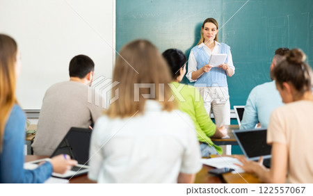 Woman teacher explaining lesson to students Woman teacher explaining lesson to students 122557067