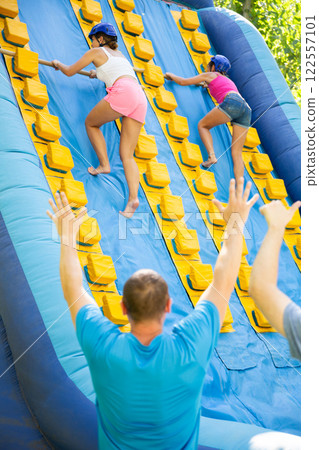 Women climbing up on slide in adventure park 122557101