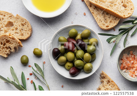 Green and black olives with olive oil, bread and himalayan pink salt on grey table 122557538