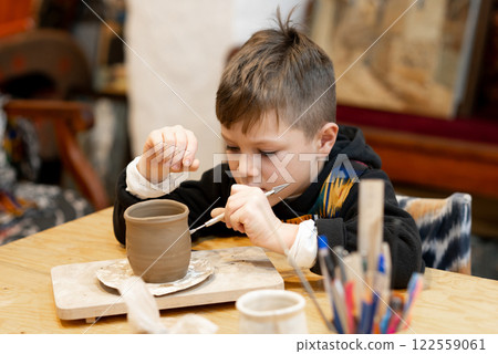 A boy creates a pot and decorating in a pottery workshop A boy creates a pot and decorating in a pottery workshop 122559061