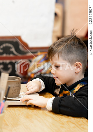 A boy creates a pot and decorating in a pottery workshop 122559074