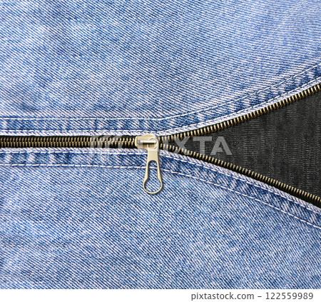 Denim zipper opened. Unzipped zipper or fastener. Open zip and denim fabric texture of blue and black color 122559989
