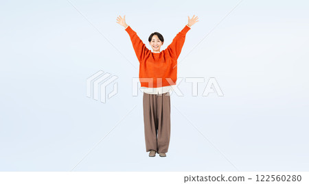 Full-body photo of a stylish middle-aged woman raising her arms in the air Full-body photo of a stylish middle-aged woman raising her arms in the air 122560280