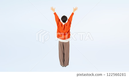 Full-body photo of a stylish middle-aged woman's backside raising her arms in the air 122560281