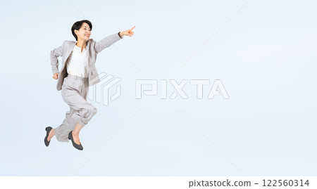 Middle-aged female business person pointing and jumping Middle-aged female business person pointing and jumping 122560314