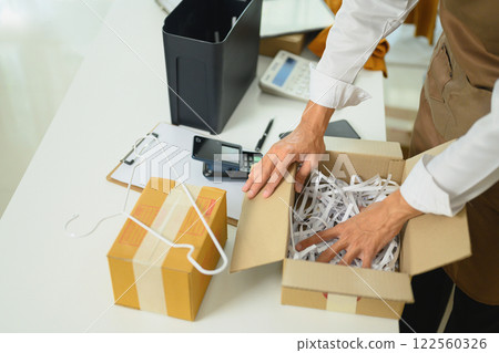 Close up of an entrepreneur preparing package with shredded paper for shipment 122560326
