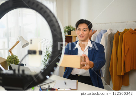 Young entrepreneur presenting a package to the camera during live online selling session Young entrepreneur presenting a package to the camera during live online selling session 122560342