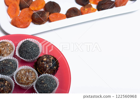 Dried fruit sweets. Balls of prunes, dates and coconut. With a sprinkle of black sesame powder. Dried fruit sweets. Balls of prunes, dates and coconut. With a sprinkle of black sesame powder. 122560968