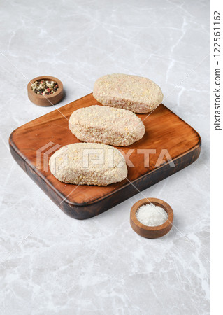 Deliciously prepared breaded cutlets on a wooden cutting board with spices Deliciously prepared breaded cutlets on a wooden cutting board with spices 122561162