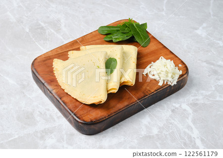 Homemade crepes with spinach and cheese on a wooden board Homemade crepes with spinach and cheese on a wooden board 122561179