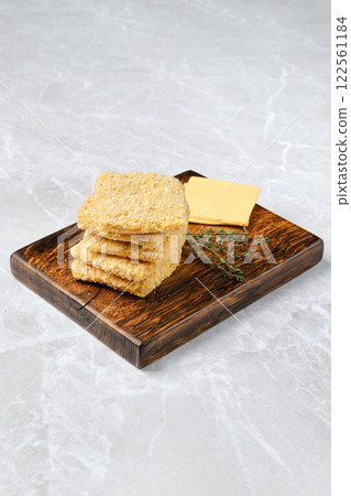 Savory cheese crackers served on a rustic wooden board with fresh herbs 122561184